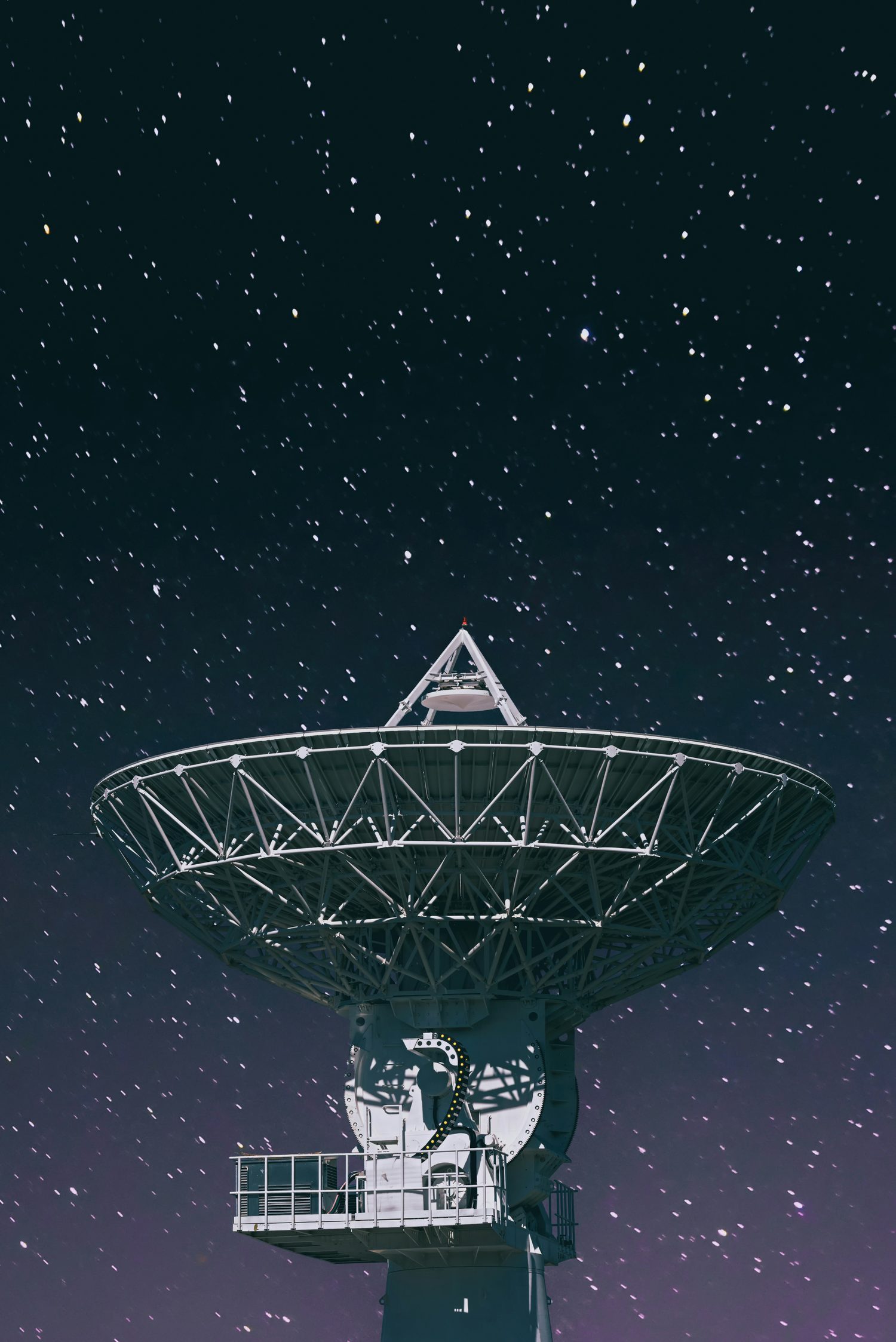 Satellite communications dish under a starry sky